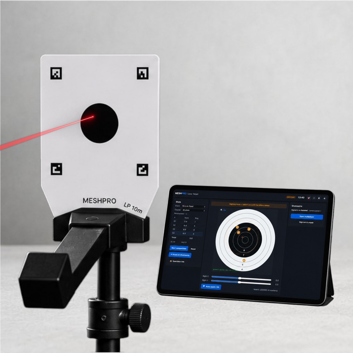 MESHPRO Laser Target auf Stativ, ein roter Laserstrahl trifft die Scheibe, daneben die Anzeige auf dem Tablet